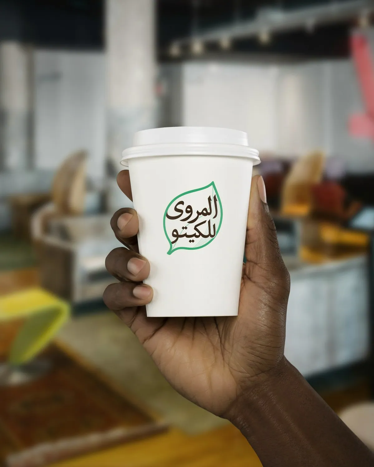 Al-Marwa logo on a takeaway cup held in a café