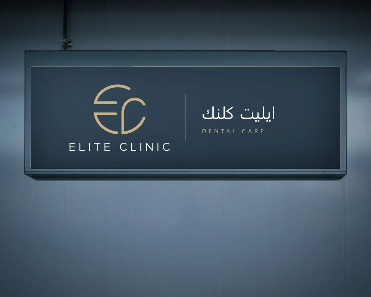 Backlit Elite Clinic sign with the Arabic name, on a blue-grey wall