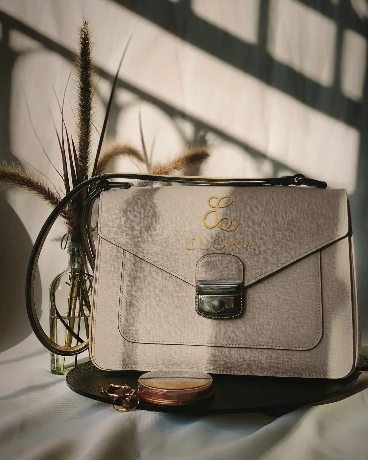 Elora logo pressed in gold into a taupe leather bag