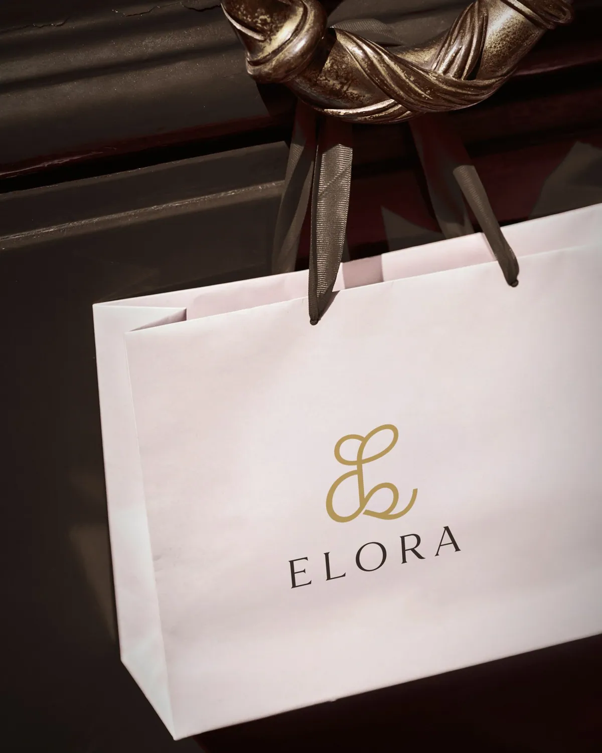 White Elora shopping bag hanging from a brass door handle