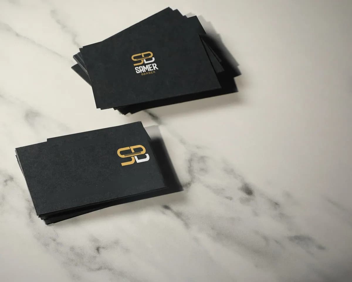 Two stacks of black Samer Barber cards on marble