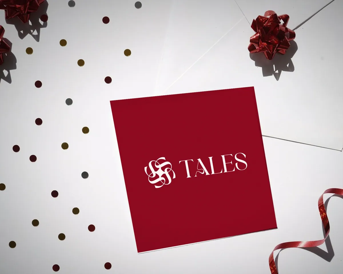 Crimson Tales card among confetti and ribbon
